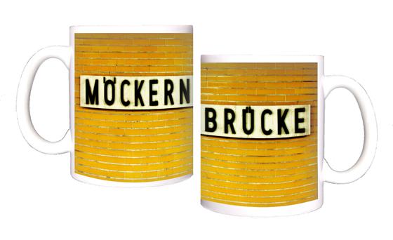 U-Bahnhof Möckernbrücke Kaffeetasse - schwarze Schrift auf weißem Schild, vor dunkelgelben Fliesen