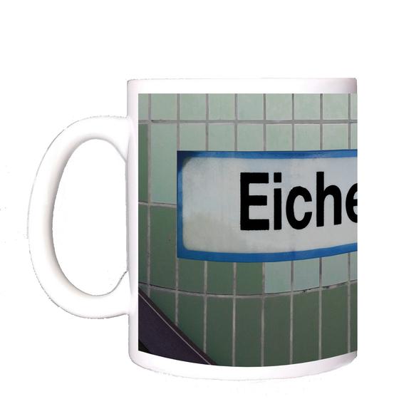 S-Bahnhof Eichenau Kaffeetasse - weißes Schild mit schwarzer Schrift und hellblauer Umrandung, auf Fliesenwand in zwei Grüntönen und weißen Fliesen