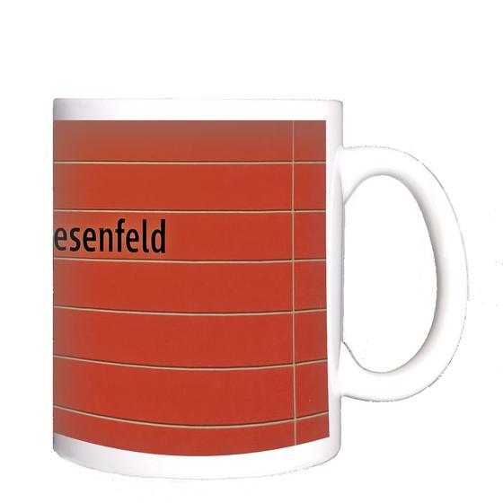 U-Bahnhof Oberwiesenfeld Kaffeetasse - schwarze Schrift auf rotem Untergrund mit grauen Querfugen