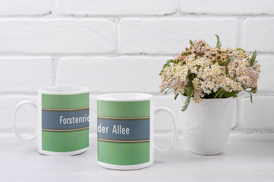 U-Bahnhof Forstenrieder Allee Kaffeetasse - weiße Schrift auf blauem Streifen, mit goldener Umrandung, vor grünem Hintergrund
