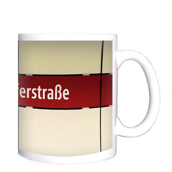 U-Bahnhof Fraunhoferstraße Kaffeetasse - weiße Schrift, auf rotem Streifen vor weißer Plattenwand