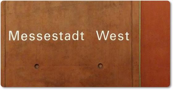 U-Bahnhof Messestadt West - weiße Schrift auf hellbrauem Hintergrund mit vereinzelten Vertiefungen