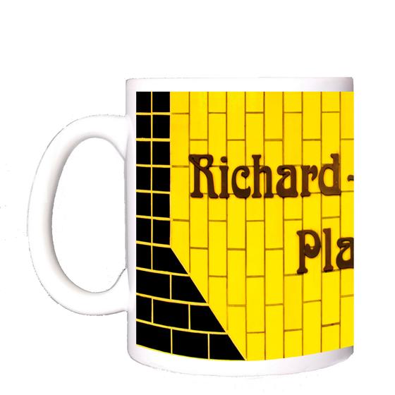 U-Bahnhof Richard-Wagner-Platz U-Bahn Souvenir Kaffeetasse - braune, verschlungene Schrift auf gelbem Kachelhintergrund, umrandet von schwarzen Kacheln