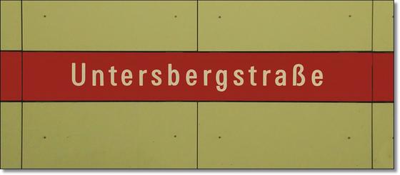 U-Bahnhof Untersbergstraße Kaffeetasse - weiße Schrift auf rotem Streifen, vor beiger Plattenwand