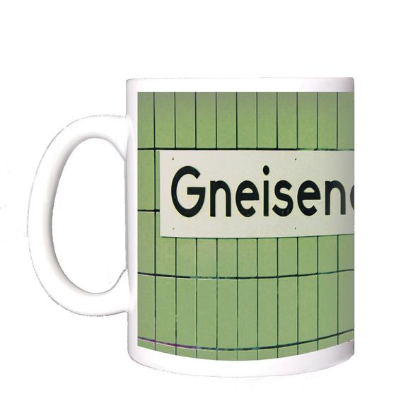 U-Bahnhof Gneisenaustraße Kaffeebecher - weißes Schild mit schwarzer Schrift, vor grüner Fliesenwand.