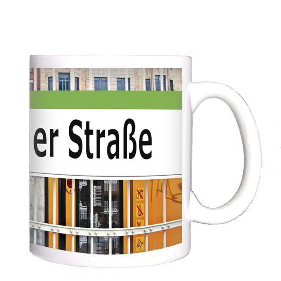 U-bahnhof Warschauer Straße Kaffeetasse - schwarze Schrift auf weißem Schild, mit grasgrünem Streifen, angebracht an einem Zaun, vor einfahrender gelber U-Bahn