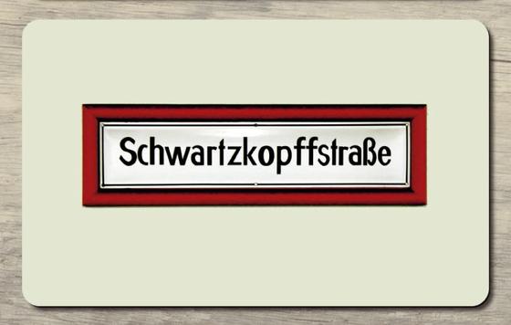 U-Bahnhof Schwarzkopffstraße Frühstücksbrettchen - weißes Schild mit schwarzer Schrift in rot-farbiger Einrahmung auf beigem Hintergrund