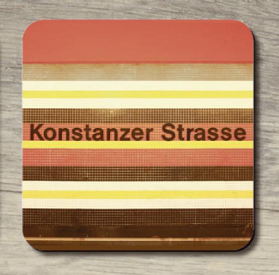 U-Bahnhof Konstanzer Strasse - schwarze Schrift vor orangen, gelben, braun, weißen Fliesenhintergrund