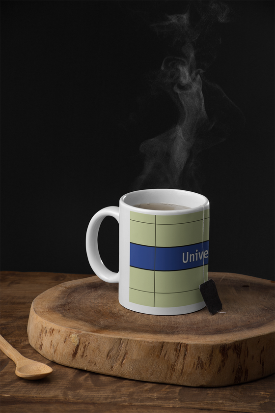 U-Bahnhof Universität Kaffeetasse - weiße Schrift auf dunkelblauem Streifen, vor weißer Plattenwand - Ansicht beide Seiten der Tasse
