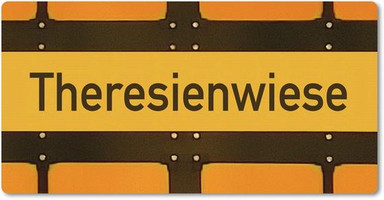U-Bahnhof Theresienwiese - schwarze Schrift auf dunkelgelbem Streifen mit schwarzer Umrandung vor orangem Hintergrund