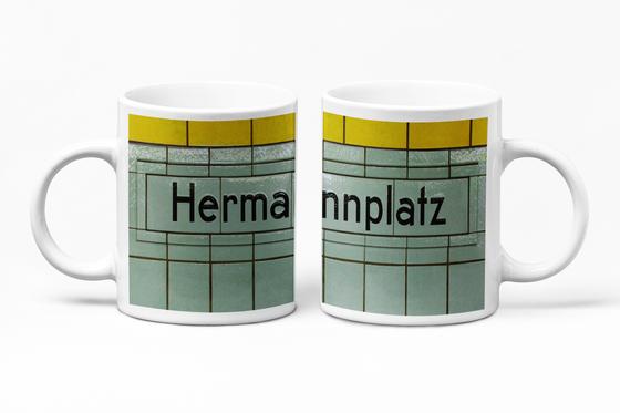 Klassischer Kaffeebecher mit original Schriftzug und Kacheln des U-Bahnhof Hermannplatz in Berlin Neukoelln - schwarze Schift  petrol-grauen Kacheln