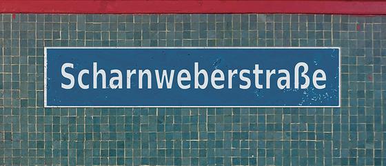 U-Bahnhof Scharnweberstraße Kaffeetasse - weiße Schrift auf dunkelblauem Schild, vor Mosaikwand in verschiedenen Blautönen, unter einem roten Streifen