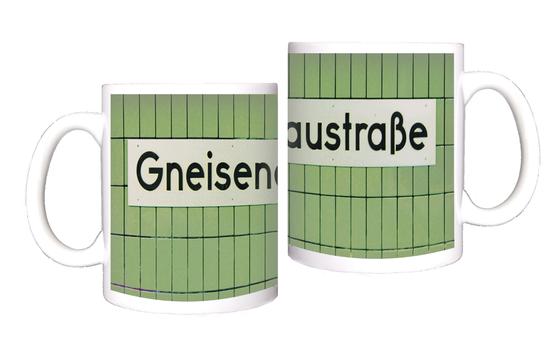U-Bahnhof Gneisenaustraße Kaffeebecher - weißes Schild mit schwarzer Schrift, vor grüner Fliesenwand.