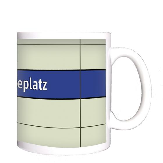 U-Bahnhof Goetheplatz Kaffeetasse - weiße Schrift auf blauem Streifen, vor weißem Plattenhintergrund