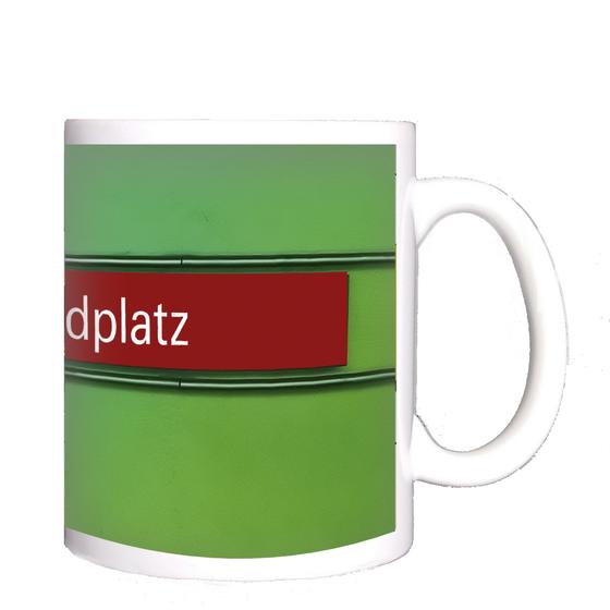 U-Bahnhof Candidplatz Kaffeetasse - weiße Schrift, auf rotem Streifen, schwarz umrandet, vor grünem Untergrund