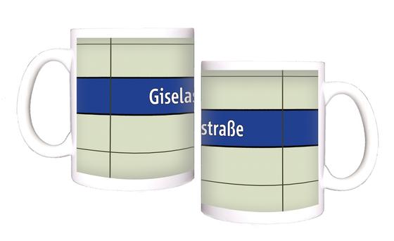 U-Bahnhof Giselastraße Kaffeetasse - weiße Schrift auf blauem Streifen, vor weißem Plattenhintergrund