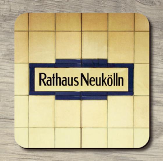 U-Bahnhof Rathaus Neukölln - schwarze Schrift auf hellem Schild mit dunkelblauer Umrahmung auf vergilbt weißen Fliesen