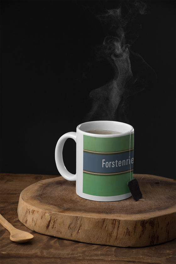 U-Bahnhof Forstenrieder Allee Kaffeetasse - weiße Schrift auf blauem Streifen, mit goldener Umrandung, vor grünem Hintergrund