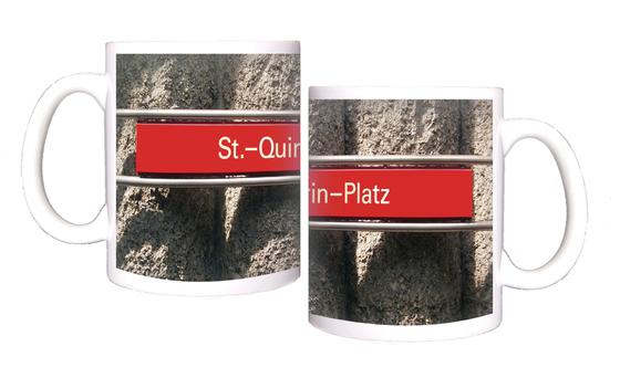 U-Bahnhof St.-Quirin-Platz Kaffeetasse - weiße Schrift auf blauem Schild, vor Betonsäulen-Wand