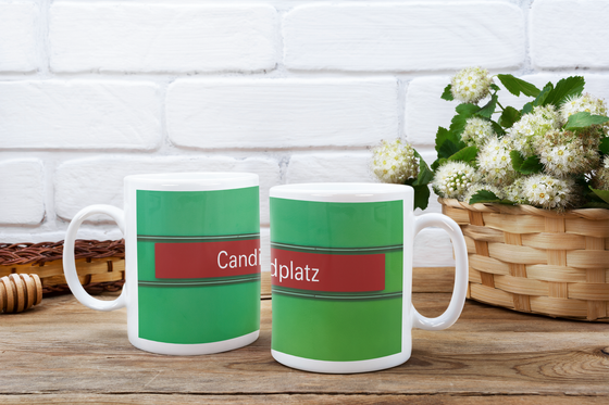 U-Bahnhof Candidplatz Kaffeetasse - weiße Schrift, auf rotem Streifen, schwarz umrandet, vor grünem Untergrund