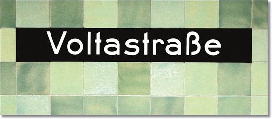 U-Bahnhof Voltastrasse Kaffeetasse - weiße Schrift auf schwarzem Schild, vor Mosaikwand in diversen Grüntönen