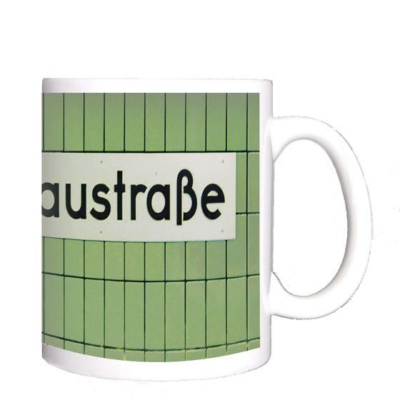 U-Bahnhof Gneisenaustraße Kaffeebecher - weißes Schild mit schwarzer Schrift, vor grüner Fliesenwand.