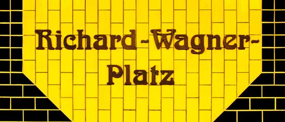 U-Bahnhof Richard-Wagner-Platz U-Bahn Souvenir Kaffeetasse - braune, verschlungene Schrift auf gelbem Kachelhintergrund, umrandet von schwarzen Kacheln