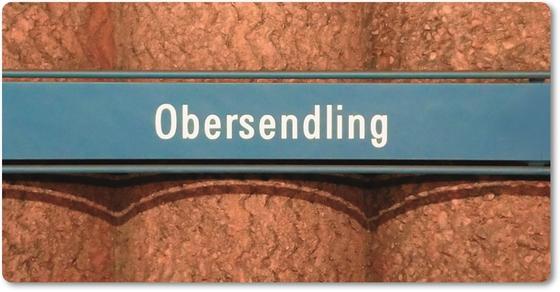U-Bahnhof Obersendling Kühlschrankmagnet  - weiße Schrift auf blauem Schild, vor Betonsäulen-Wand