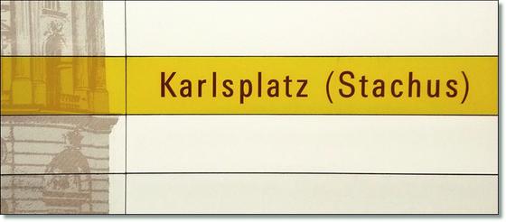 U-Bahnhof Karlsplatz Stachus Kaffeetasse - schwarzer Schrift auf gelbem Streifen, vor weißem Plattenhintergrund 