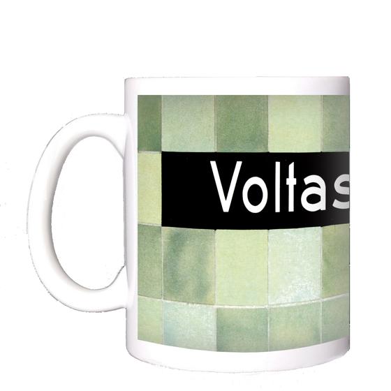 U-Bahnhof Voltastrasse Kaffeetasse - weiße Schrift auf schwarzem Schild, vor Mosaikwand in diversen Grüntönen