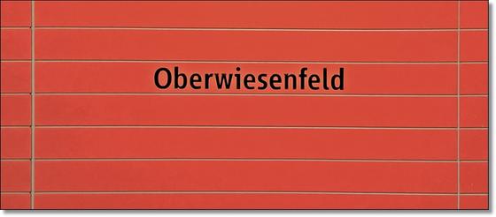 U-Bahnhof Oberwiesenfeld Kaffeetasse - schwarze Schrift auf rotem Untergrund mit grauen Querfugen