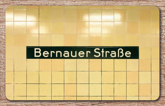 U-Bahnhof Bernauer Strasse Frühstücksbrettchen - schwarzes Schild mit weißer Schrift auf beigem Fliesenhintergrund