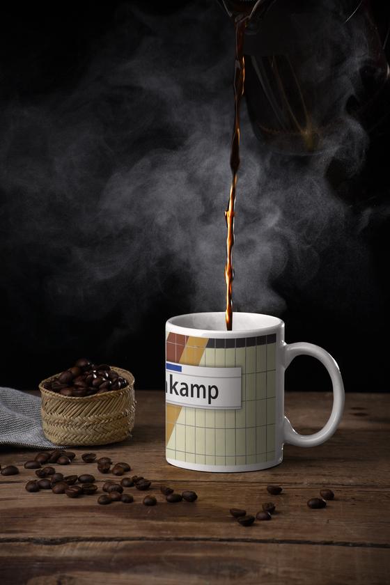 S-Bahn Hamburg Kaffeebecher Kaffeetasse S-Bahnhof Lattenkamp beige Fliesen mit orang, rot gelbem Muster, darüber weißes Schild mit schwarzer Schrift tom bäcker, Geschenkidee, 