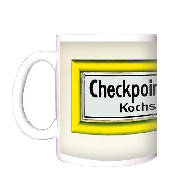 U-Bahnhof Checkpoint Charlie Kochstrasse Kaffeetasse - schwarze Schrift auf weißem Schild mit gelbem Rahmen, vor weisser Wand
