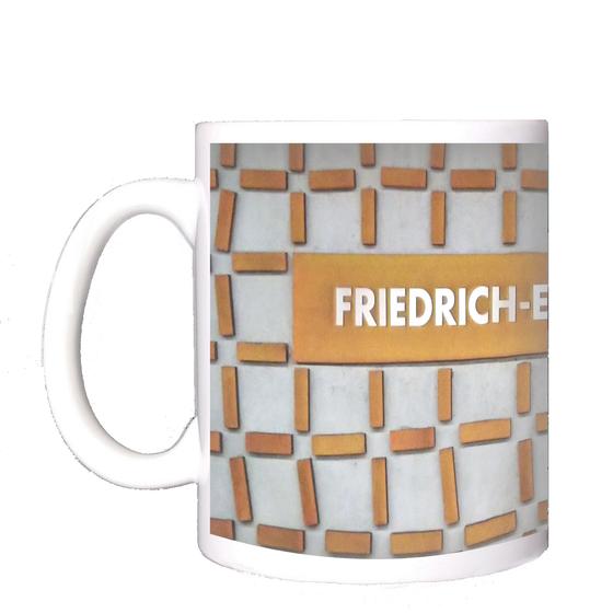 U-Bahn-Tasse Nuernberg Friedrich-Ebert-Platz der Linie U3 in der originalgetreuen Stations-Gestaltung - Hellblaugraue Wand mit rostig orangener Netzstruktur, Schild in gleicher Farbe mit weisser Schrift