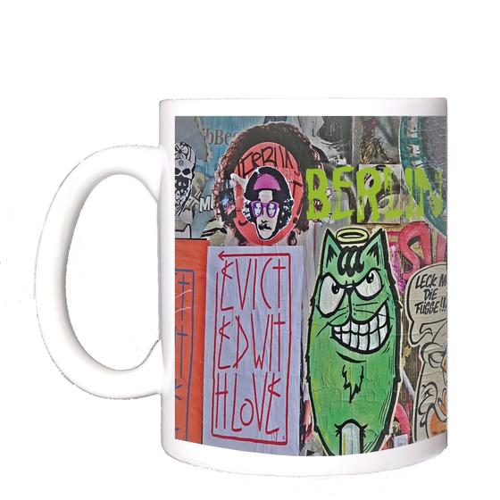 Klassischer Kaffeebecher aus weisser Keramik mit einem Foto einer bunten Streetart-Wand mit Berlin-Schriftzug in Berlin Friedrichshain - beklebt und bemalt von vielen verschiedenen Künstlern 