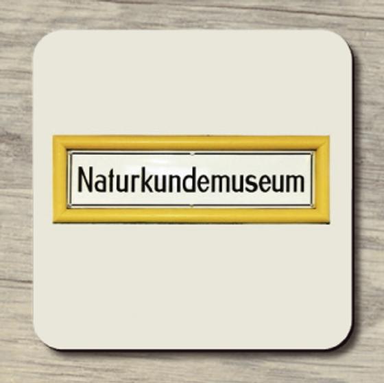 U-Bahnhof Naturkundemuseum - schwarze Schrift auf weißem Schild mit gelber Umrahmung auf hellbeigem, fast weißem Hintergrund