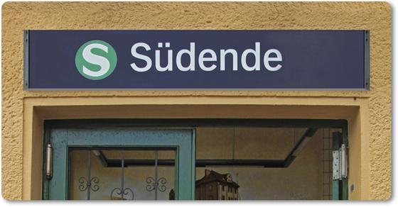 S-Bahnhof Südende S26 Kaffeetasse - weisse Schrift auf blauem Schild über Eingangstür - Umrahmt von beige-brauner Rauputz-Wand