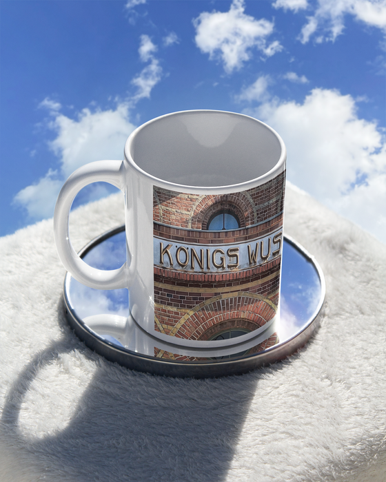 S-Bahnhof Koenigswusterhause Kaffetasse braune Schrift auf grauem Streifen an Backsteinhaus mit Fenstern