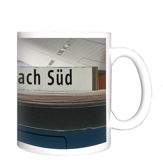 U-Bahnhof Neuperlach Süd Kaffeetasse - schwarze Schrift auf weißem Schild, in U-Bahnhof mit spitz zulaufender Decke