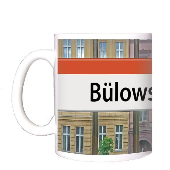 U-Bahnhof Kaffeetasse Bülowstrasse - schwarze Schrift auf weißem Schild mit orangem Streifen, an Bahnhofsfenster befestigt mit rotem und gelbem Haus im Hintergrund