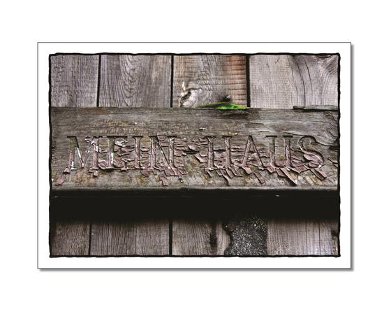 Klassische Postkarte - Home Sweet Home. Fotografie des Schriftzuges "Mein Haus" auf einem Holzbalken. 