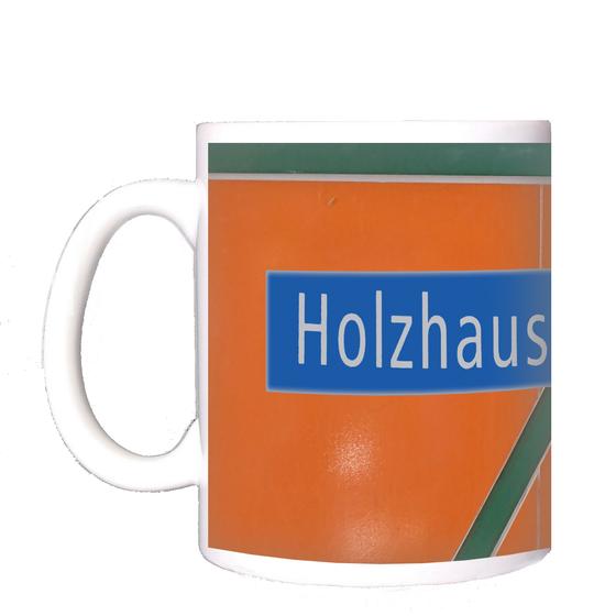 U-Bahnhof Holzhauser Straße Kaffeetasse - weiße Schrift auf blauem Schild vor orangem Hintergrund mit dunkelgrünem, diagonalem Streifen
