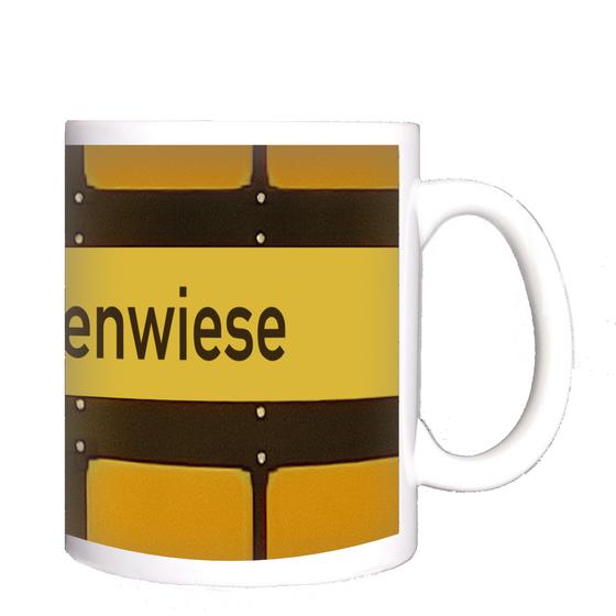 U-Bahnhof Theresienwiese Tasse - schwarze Schrift auf gelbem Schild, vor gelbem Hintergrund mit schwarzen Umrandungen