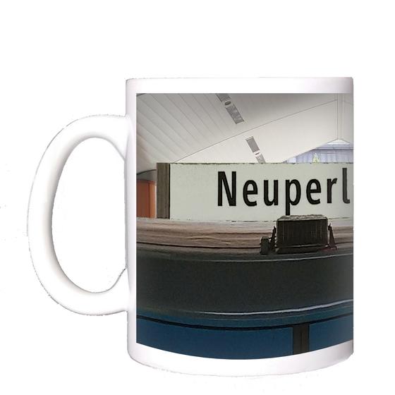 U-Bahnhof Neuperlach Süd Kaffeetasse - schwarze Schrift auf weißem Schild, in U-Bahnhof mit spitz zulaufender Decke