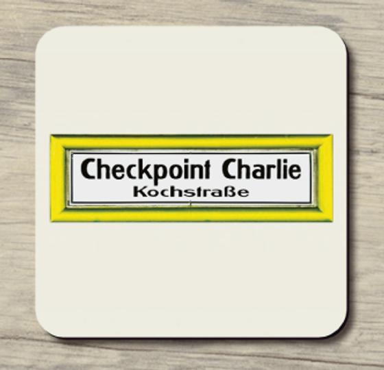 U-Bahnhof Kochstraße Checkpoint Charlie - schwarze Schrift auf weißem Schild mit gelber Umrandung auf hellbeigem Hintergrund