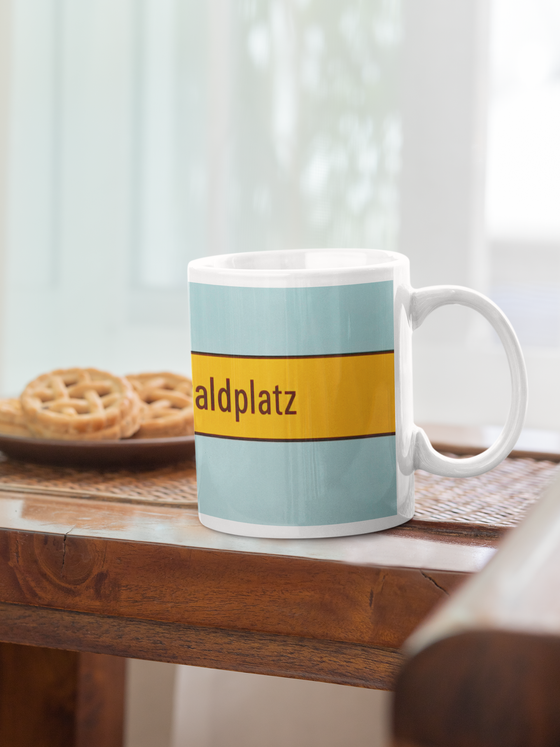 U-Bahn-Tasse München Böhmerwaldplatz der Linie U4 in der originalgetreuen Stations-Gestaltung - schwarze Schrift auf gelbem Streifen, bläulicher Hintergrund