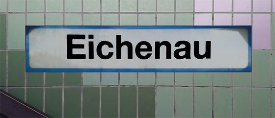 S-Bahnhof Eichenau Kaffeetasse - weißes Schild mit schwarzer Schrift und hellblauer Umrandung, auf Fliesenwand in zwei Grüntönen und weißen Fliesen