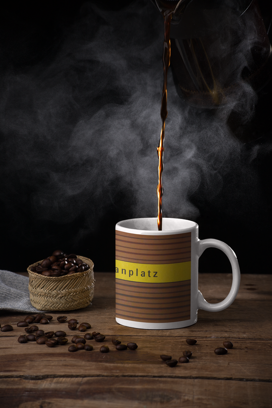U-Bahnhof Heimeranplatz Kaffeetasse - schwarze Schrift auf gelbem Streifen, vor braunem Riffelhintergrund