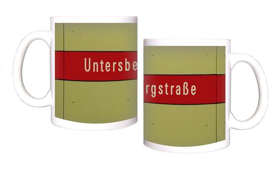 U-Bahnhof Untersbergstraße Kaffeetasse - weiße Schrift auf rotem Streifen, vor beiger Plattenwand